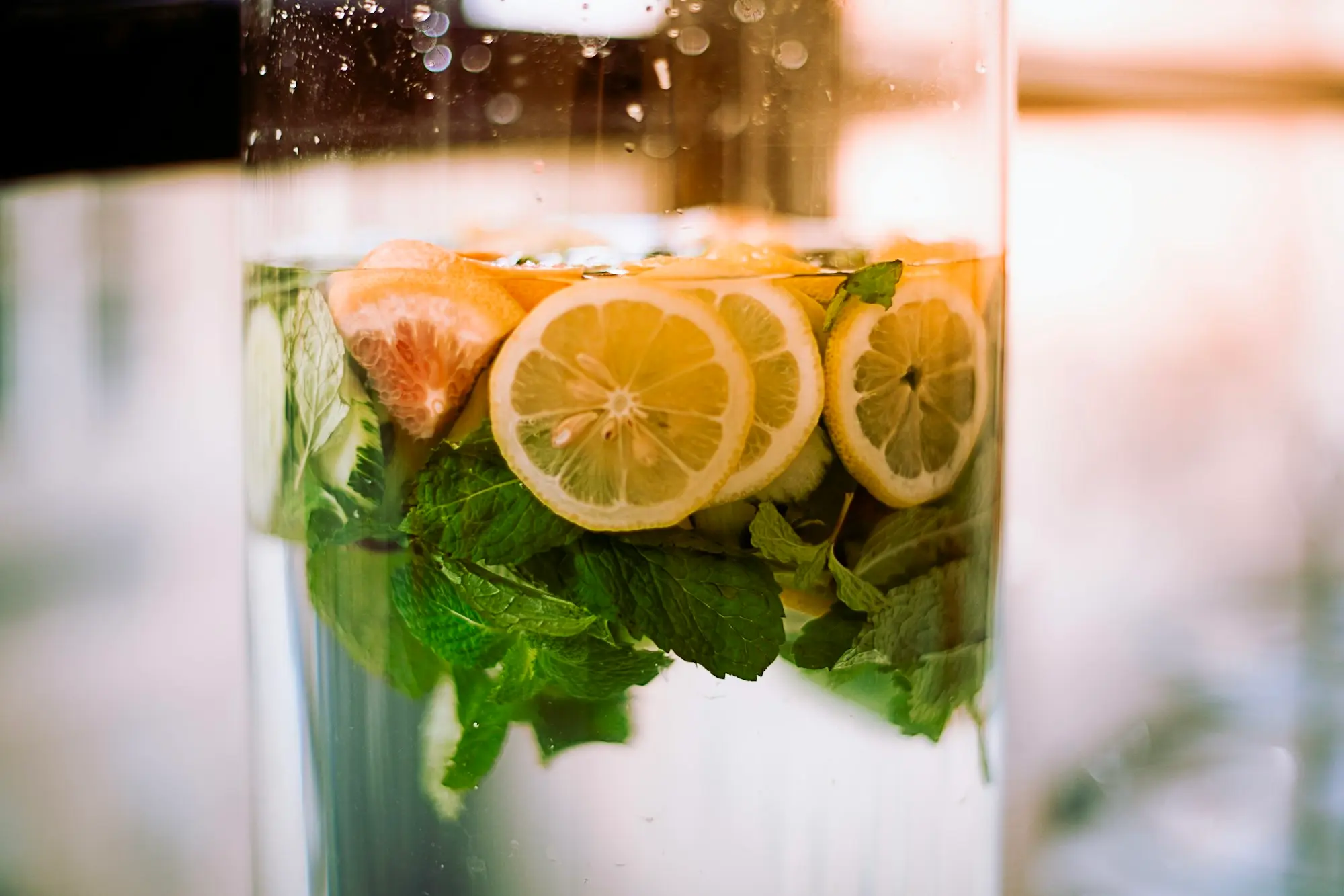 Carafe d'eau avec des rondelles de citron, un quartier de pamplemousse et des feuilles de menthe