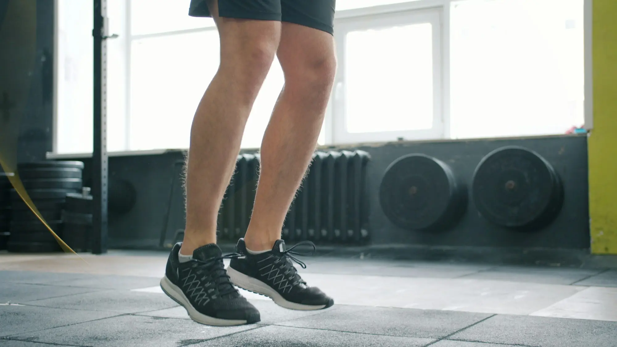 Jambes d'un sportif qui saute à la corde dans une salle de sport lumineuse