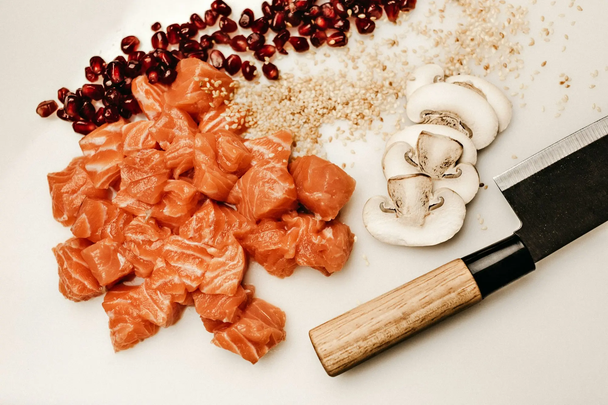 Dés de saumon cru, champignons, graines et grenade préparés sur un plan de travail clair