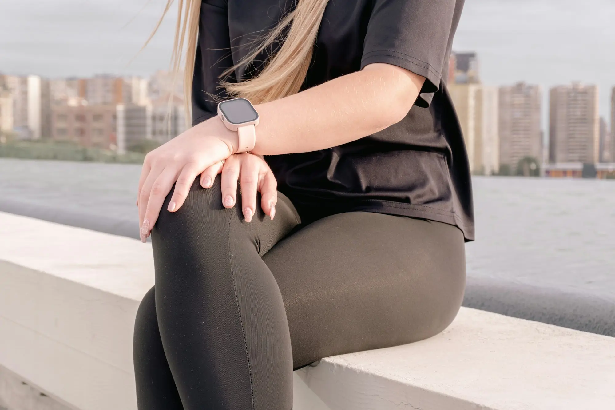 Sportive assise sur un muret qui se tient la jambe au niveau du genou
